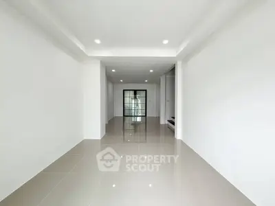 Spacious modern interior with sleek tile flooring and recessed lighting, perfect for versatile living space.