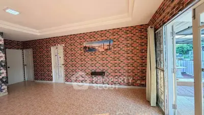 Spacious living room with brick accent wall and large windows for natural light.