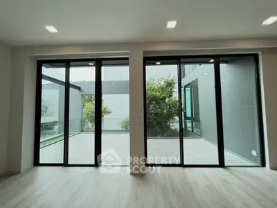 Spacious modern living room with large glass doors opening to a private balcony.