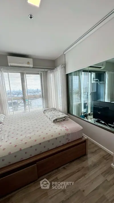 Modern bedroom with large windows offering stunning city views, featuring sleek wooden flooring and contemporary decor.
