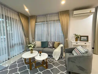 Elegant living room with modern decor, featuring a cozy gray sofa, stylish armchair, and chic coffee tables.