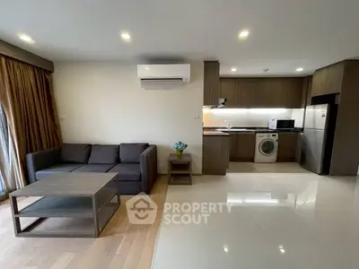 Modern open-plan living room with sleek kitchen and cozy seating area, featuring a washing machine and air conditioning.