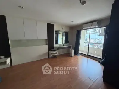 Spacious bedroom with balcony and city view, featuring hardwood floors and modern built-in furniture.