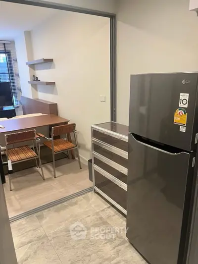 Modern kitchen with sleek fridge and dining area in open layout apartment.