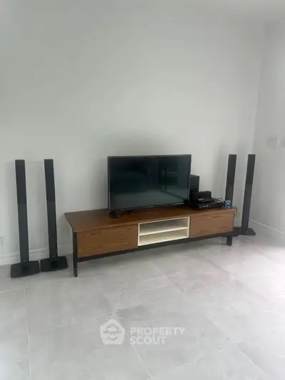 Modern living room with sleek TV stand and sound system on polished tile floor.