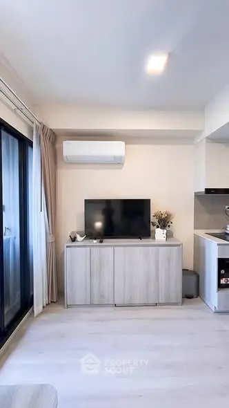 Modern living room with sleek TV setup and air conditioning, adjacent to a stylish kitchen area.