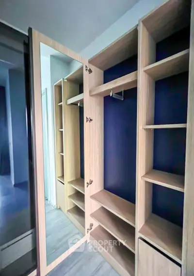 Spacious walk-in closet with modern wooden shelving and mirrored door.