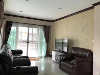 Spacious living room with leather sofas and large window for natural light.