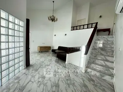 Spacious living room with marble flooring and elegant staircase in a modern home.
