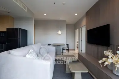 Modern living room with sleek design and neutral tones, featuring a wall-mounted TV and stylish furniture.