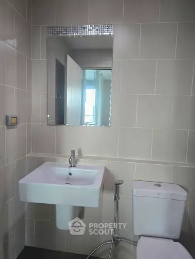 Modern bathroom with sleek sink and toilet in a tiled setting