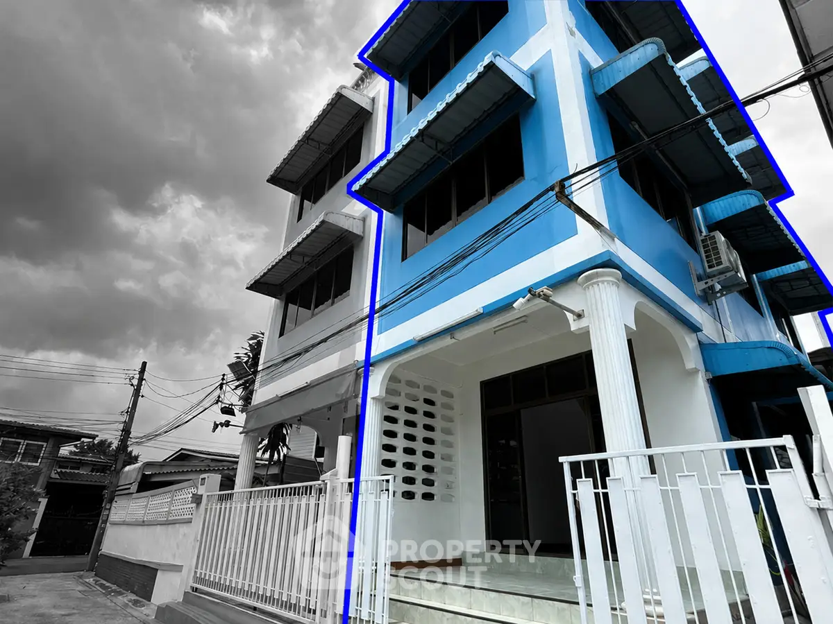 Striking blue and white exterior of a modern multi-story building with a gated entrance.