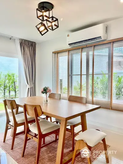 Elegant dining area with modern wooden table and chairs, large windows, and stylish lighting.