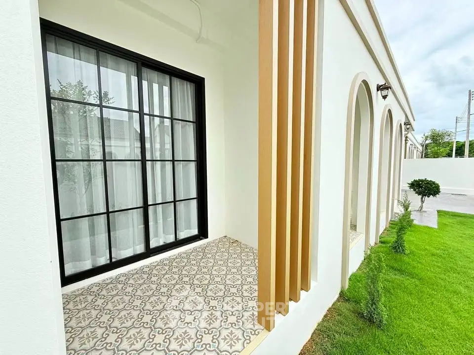 Charming exterior view of modern home with elegant arches and lush green lawn.
