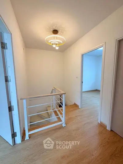 Bright hallway with wooden flooring and modern light fixture in a contemporary home.