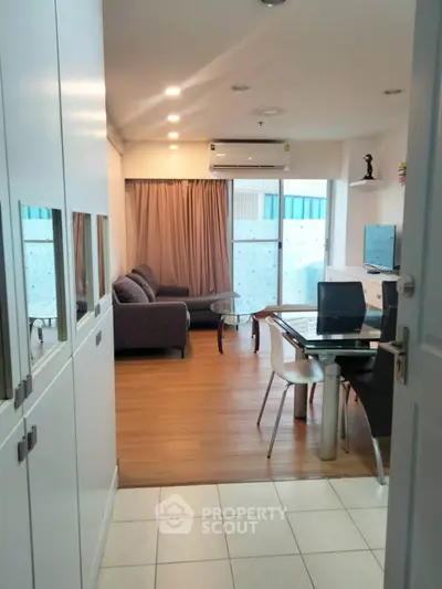 Modern living room with dining area, featuring sleek furniture and natural light.