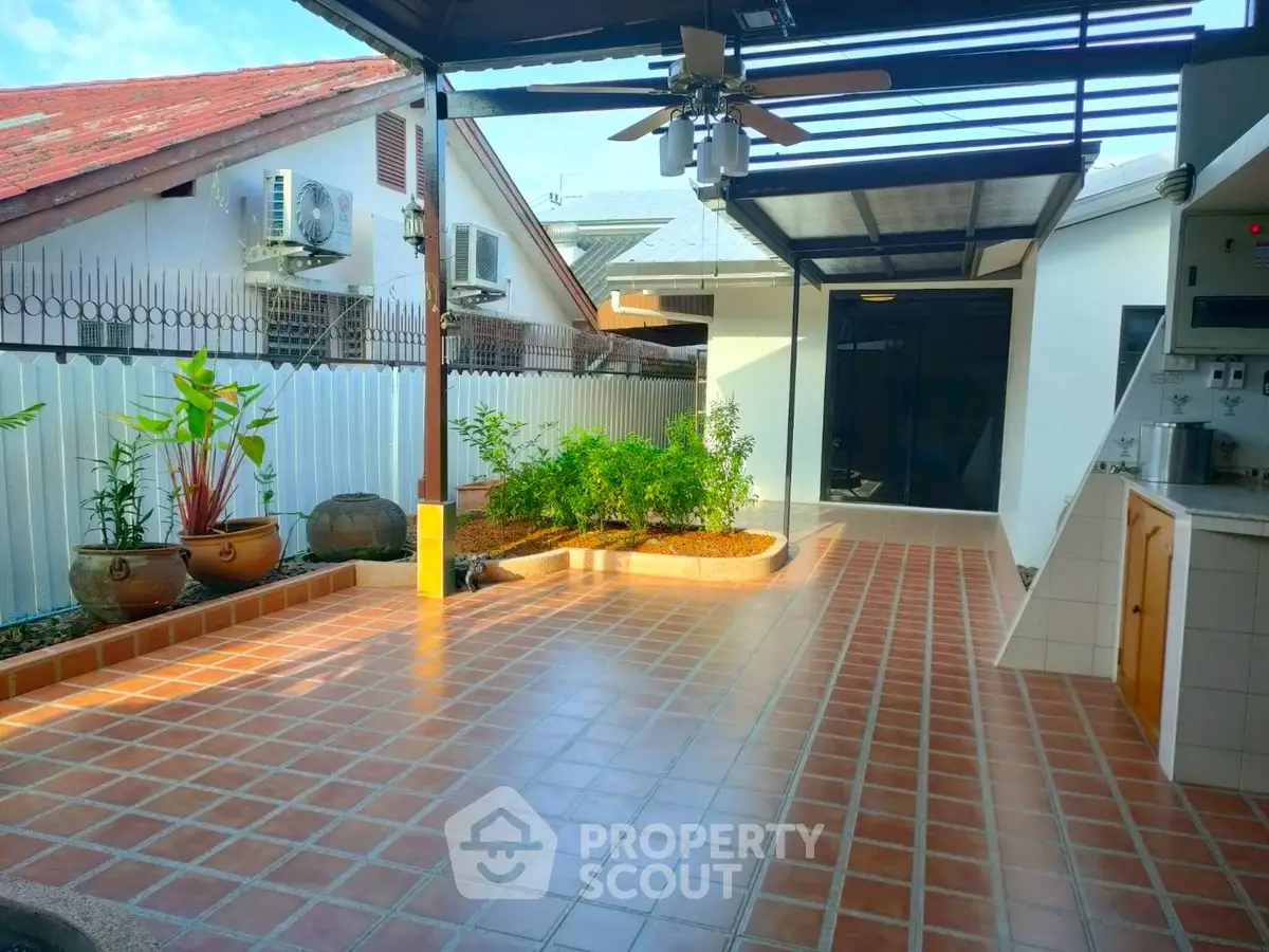 Spacious tiled patio with ceiling fan and garden area in modern home
