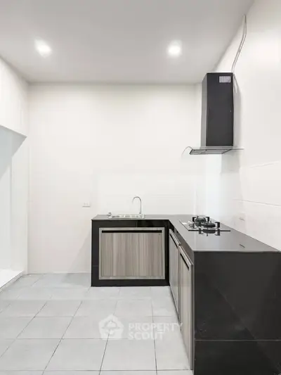 Modern kitchen with sleek black countertops and gas stove in a minimalist design.