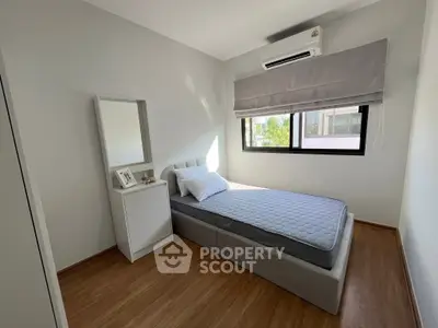 Cozy bedroom with single bed, air conditioning, and natural light through large window.