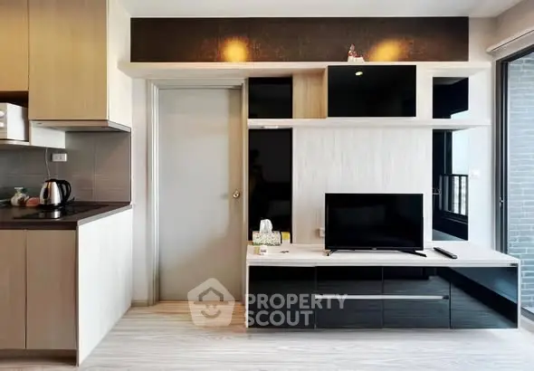 Modern living room with sleek TV unit and adjacent kitchen area, showcasing contemporary design and functionality.