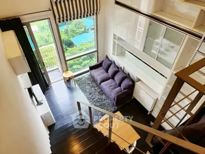 Modern loft-style living room with large windows and scenic view, featuring a cozy purple sofa and sleek black staircase.