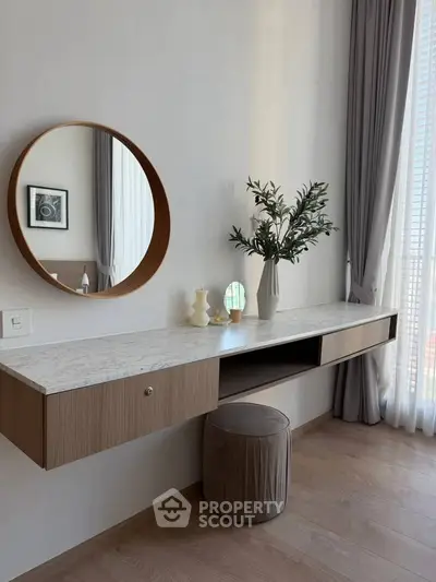 Elegant bedroom vanity with round mirror and modern decor in a stylish apartment.