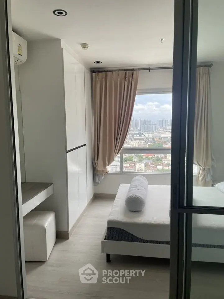 Modern bedroom with city view, featuring sleek white furniture and large window for natural light.
