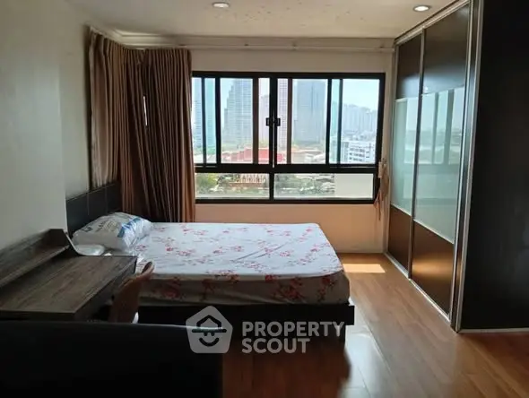 Spacious bedroom with large window offering city view and ample natural light.