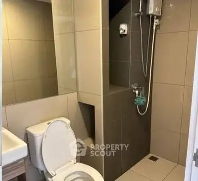 Modern bathroom with sleek tiles and compact shower area in a contemporary apartment.