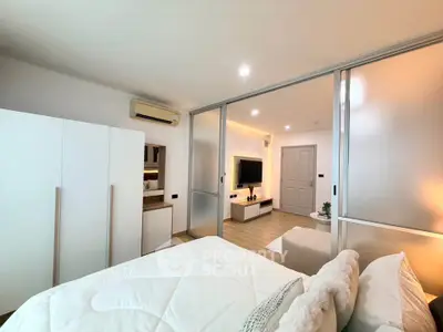 Modern bedroom with sliding glass doors leading to a cozy living area, featuring stylish decor and ample natural light.