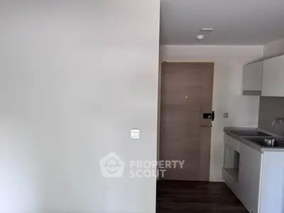 Modern minimalist kitchen with sleek cabinetry and stainless steel sink in compact apartment.