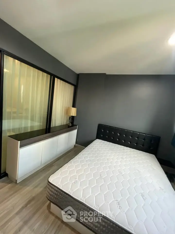 Modern bedroom with sleek design and large window, featuring a comfortable bed and stylish furniture.