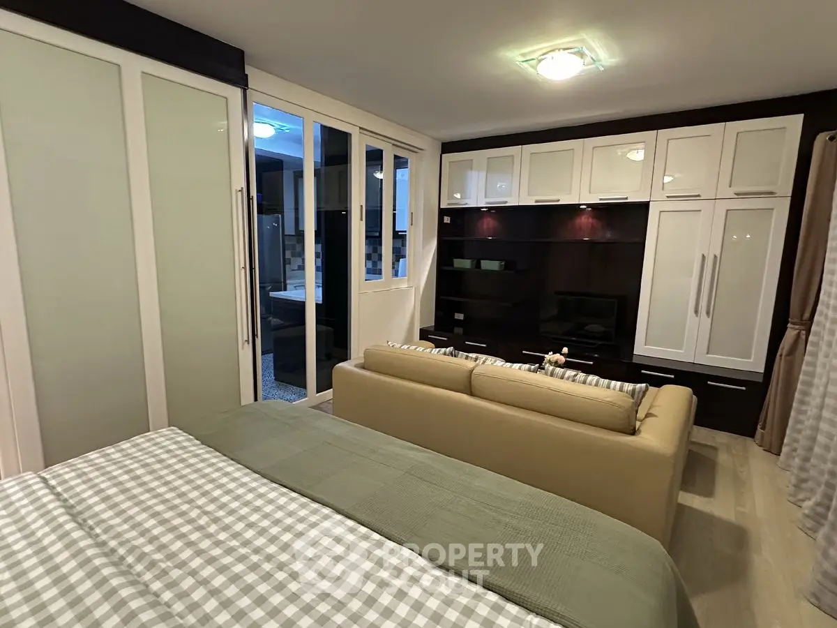 Spacious bedroom with modern built-in storage and cozy seating area.