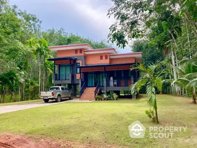 Modern two-story house with lush garden and driveway in tropical setting