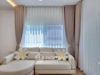Elegant living room with stylish sofa and floral cushions, featuring floor-to-ceiling curtains for a cozy ambiance.