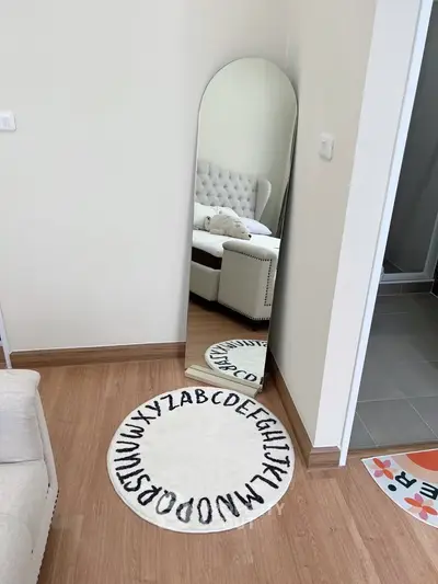 Stylish bedroom corner with a full-length mirror and alphabet rug, modern decor