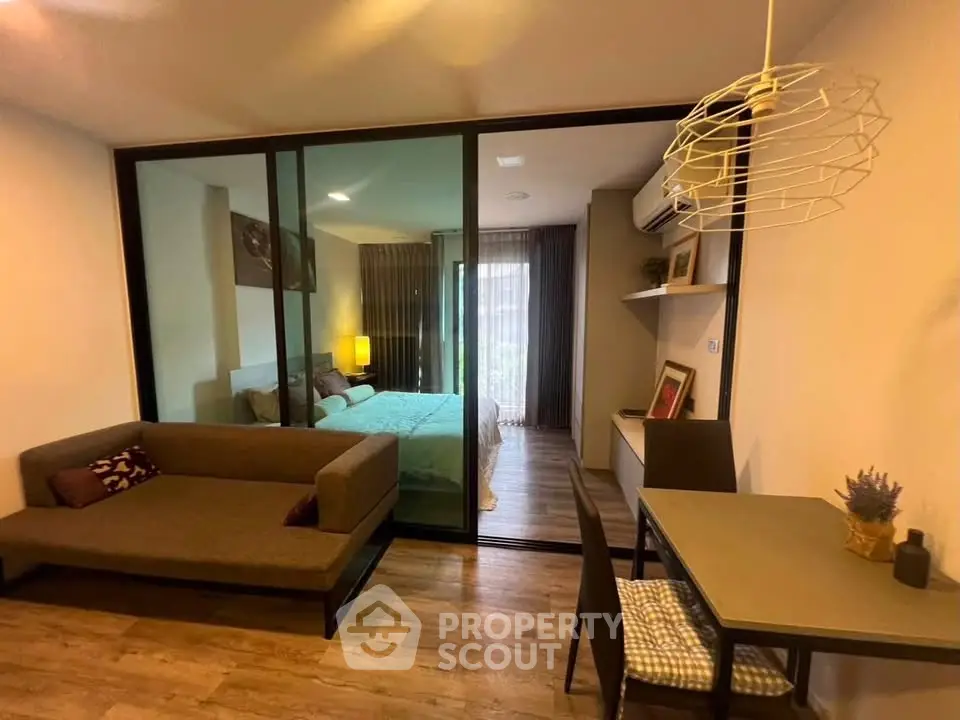 Modern studio apartment with glass partition, cozy living area, and stylish decor.