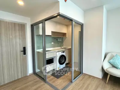Modern compact kitchen with washing machine and glass enclosure in stylish apartment.