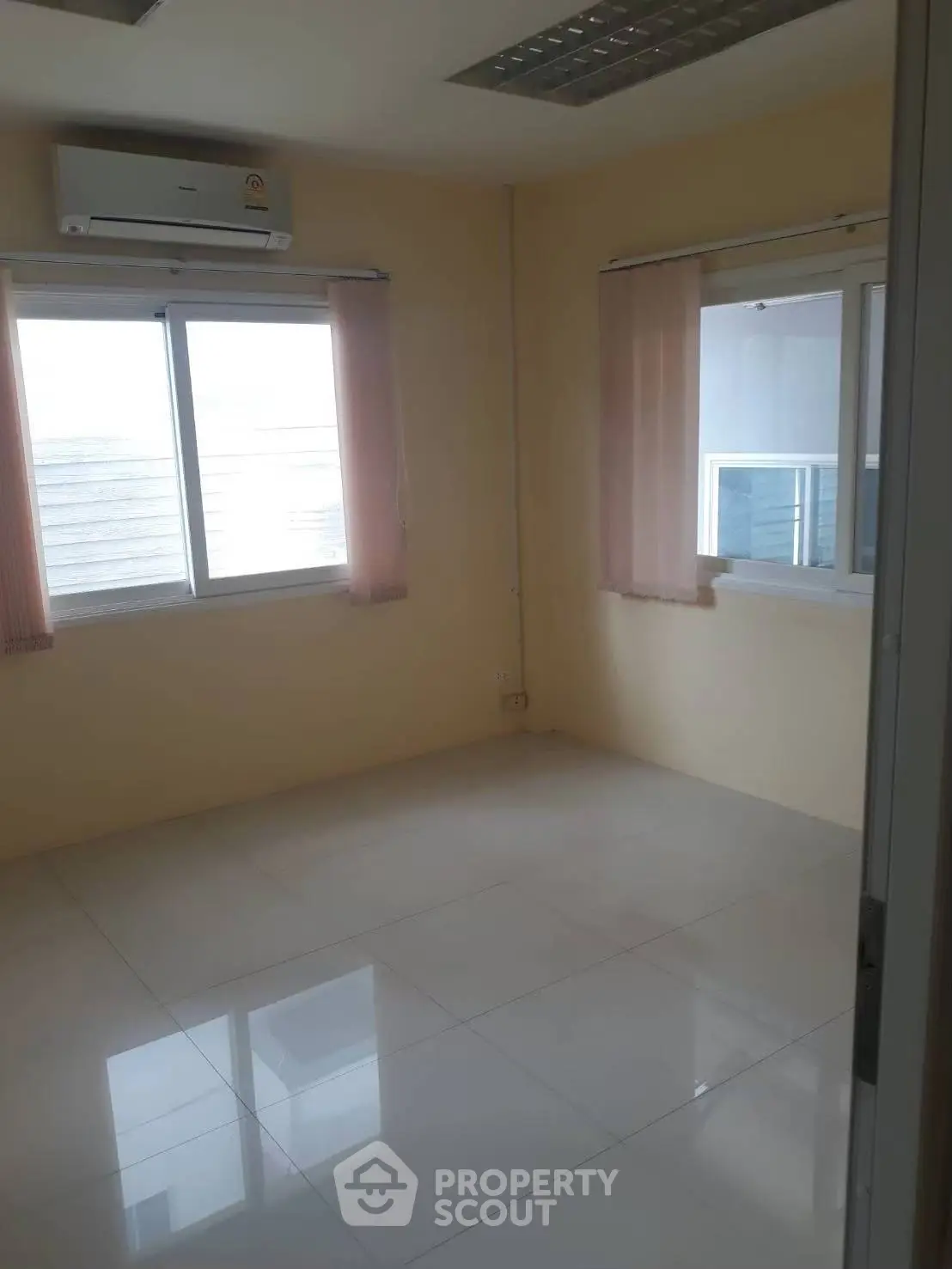 Bright empty room with large windows and air conditioning, perfect for customization.