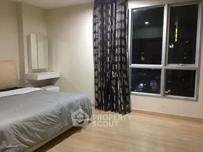 Spacious bedroom with city view and modern decor in high-rise apartment.
