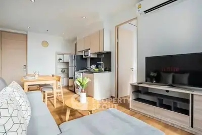 Modern living room with open kitchen, stylish furniture, and natural light.