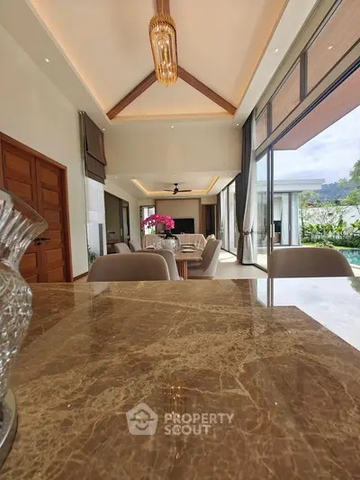 Luxurious open-plan living room with high ceilings and elegant decor, featuring a stunning view through large windows.