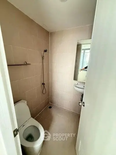 Compact bathroom with modern fixtures and neutral tiles, ideal for urban living.