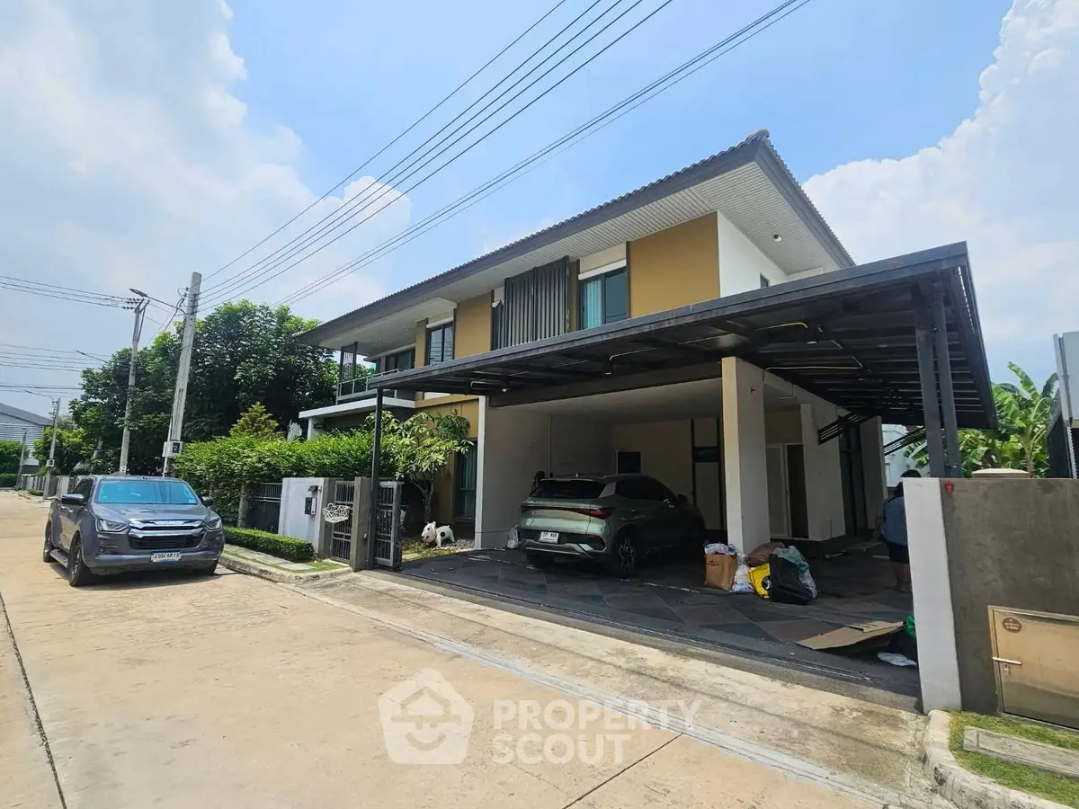 Modern two-story house with carport and lush greenery in a serene neighborhood.