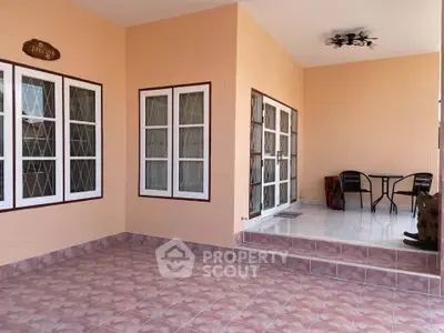 Spacious tiled patio with seating area and large windows, perfect for outdoor relaxation.
