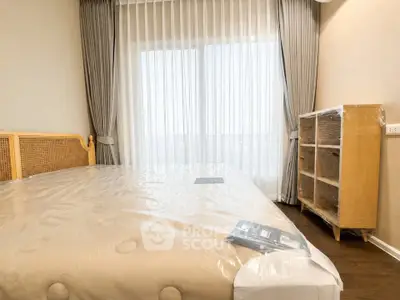 Spacious bedroom with elegant furnishings and large window offering natural light.