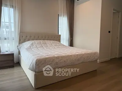 Spacious bedroom with elegant bed and natural light from large windows.