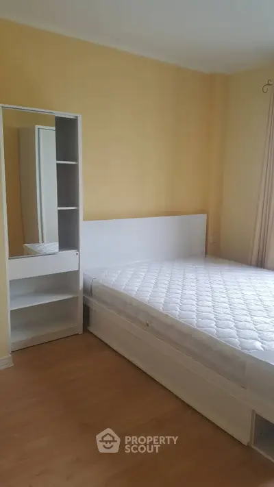Cozy bedroom with minimalist white furniture and soft yellow walls.
