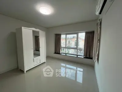 Spacious bedroom with large window and wardrobe, offering ample natural light and modern design.