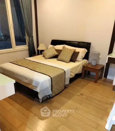 Cozy bedroom with wooden flooring and elegant decor in a modern apartment.